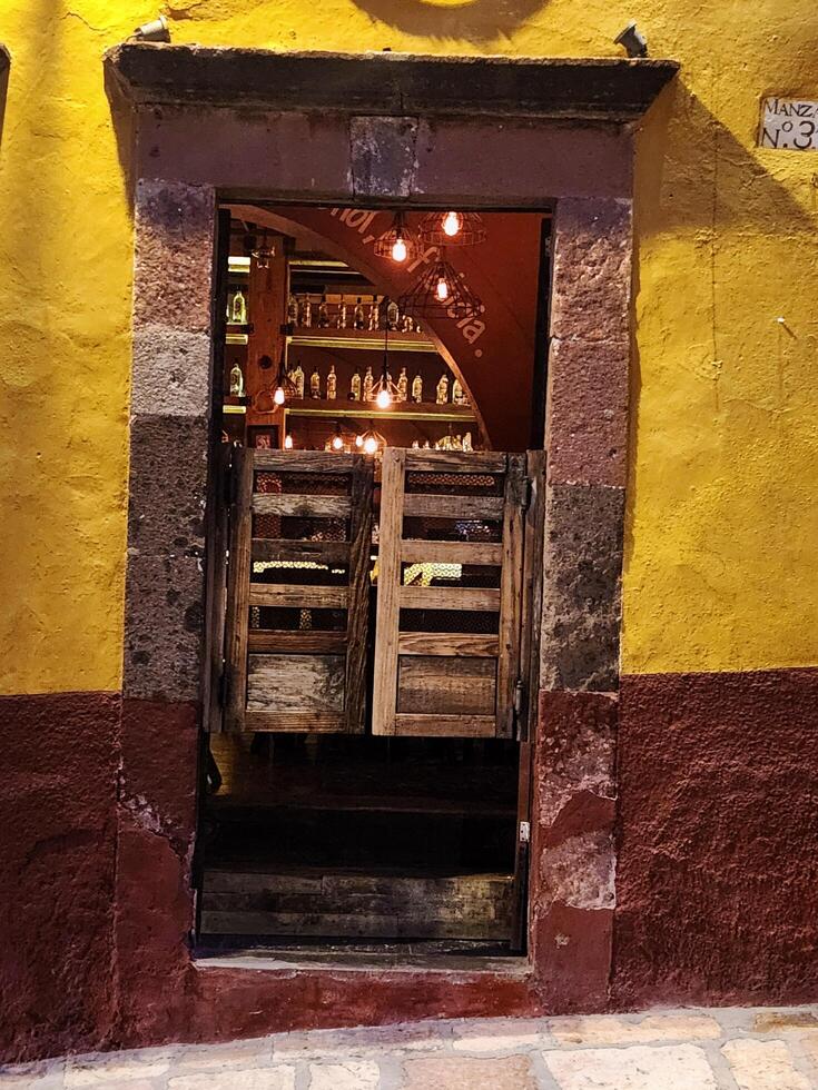 A yellow and red building with a door and a clock on the wall photo