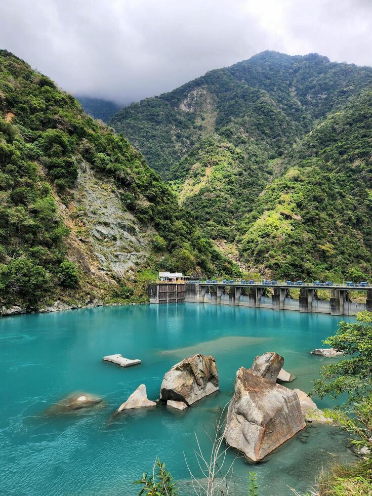 A blue lake surrounded by mountains and a dam photo
