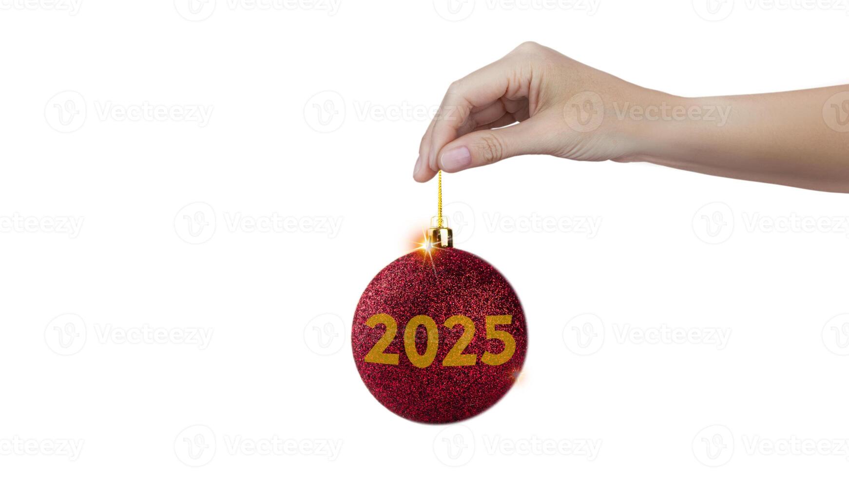 A woman's hand holds a red shiny Christmas tree ball with the inscription 2025 isolated on white background photo