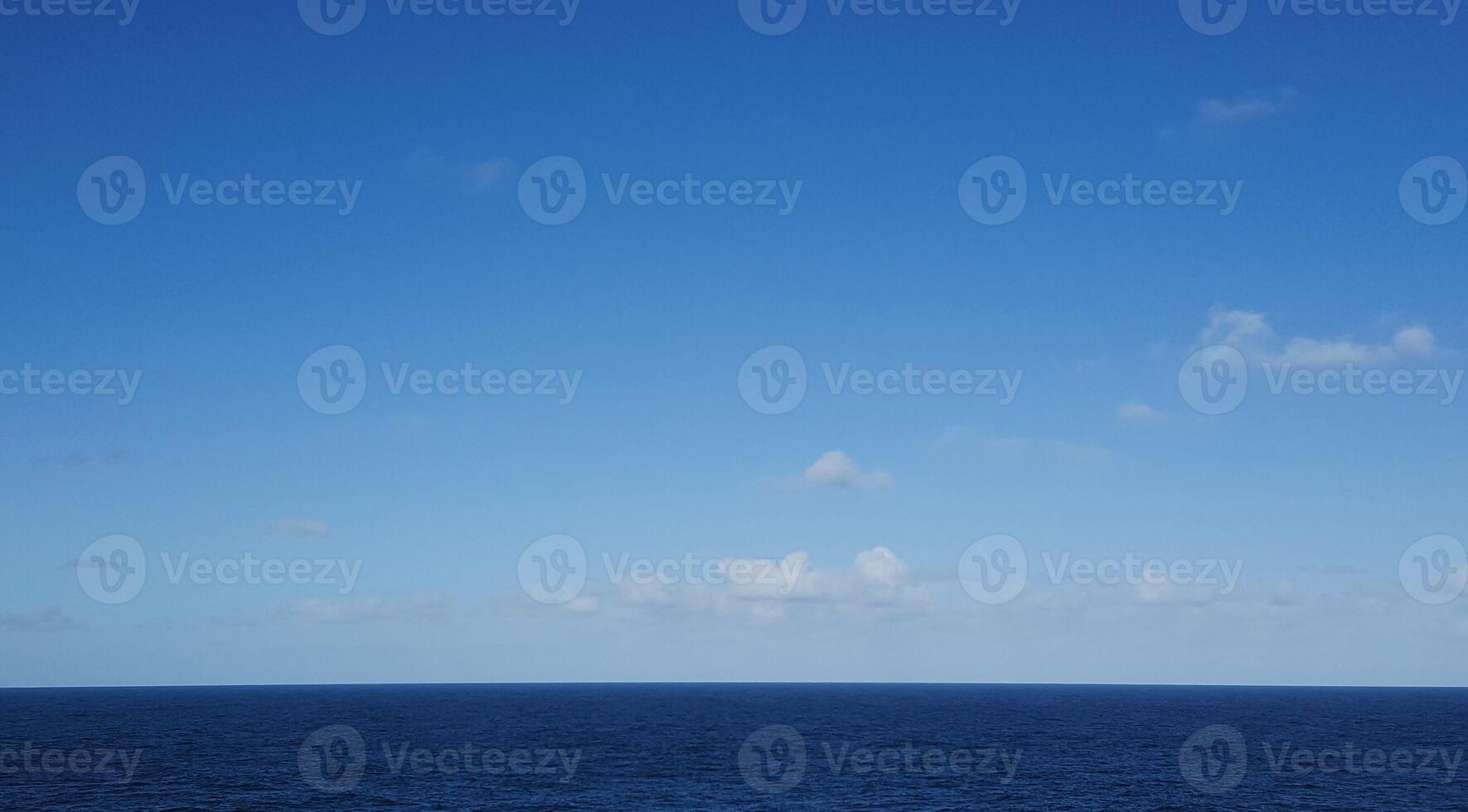 A blue sky with clouds and a boat in the ocean photo