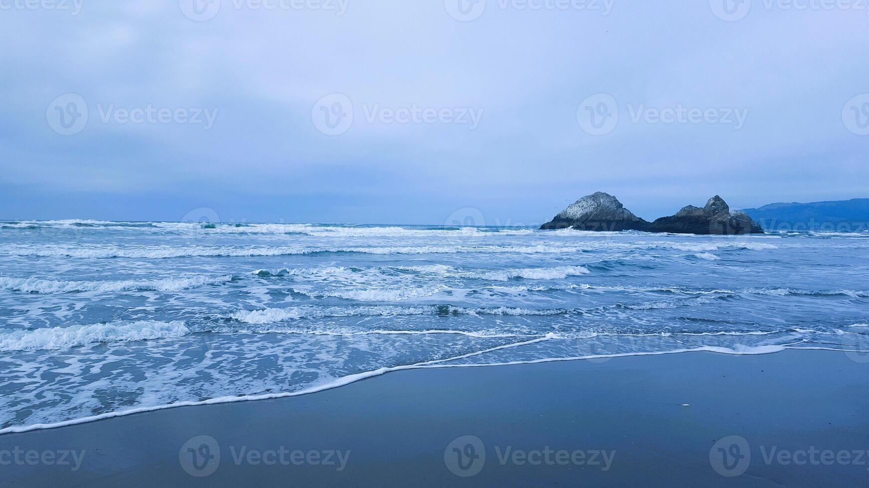A view of the ocean and some rocks on the beach photo