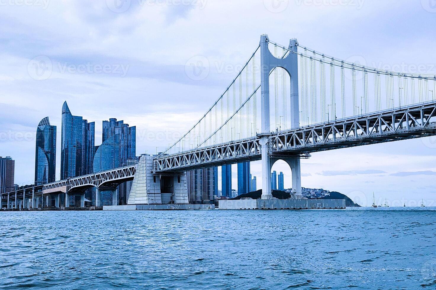 A bridge spanning across the water with tall buildings in the background photo