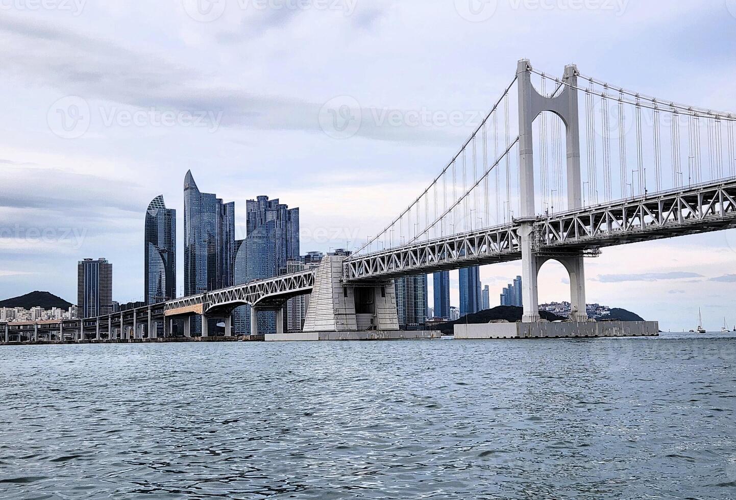 A bridge spanning across the water with tall buildings in the background photo