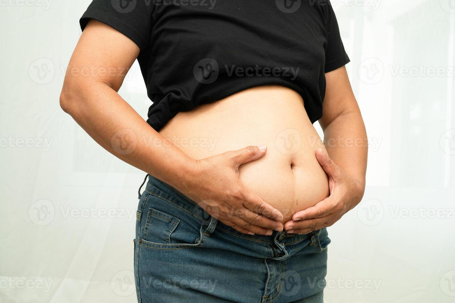 Overweight asian woman use hand to squeeze fat belly big size overweight and obesity. photo