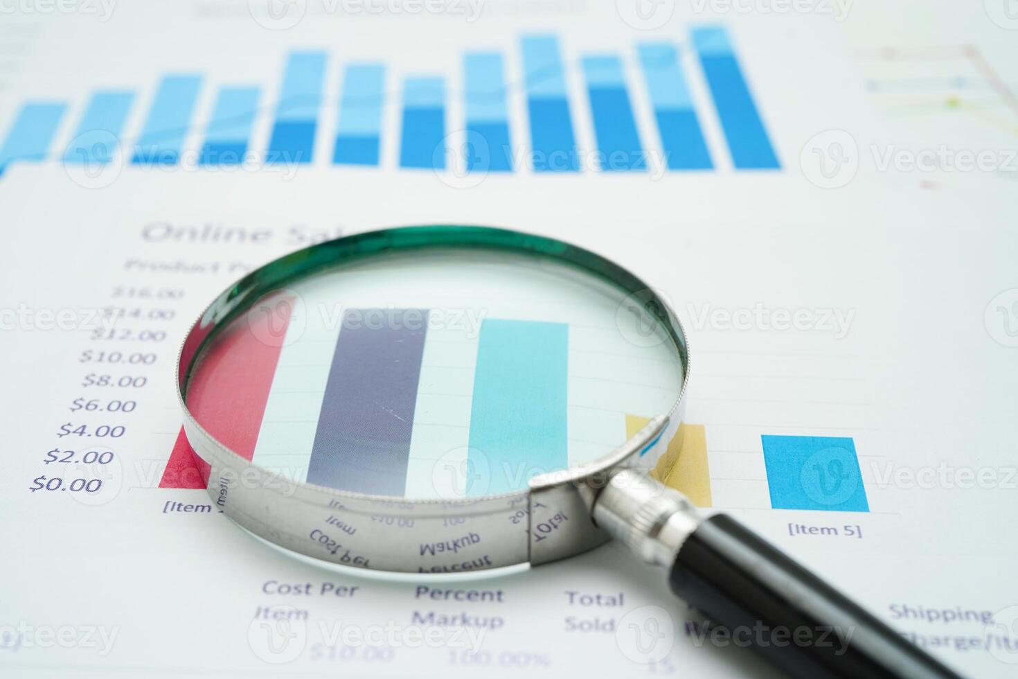 Magnifying glass on charts graphs paper. finance business. photo