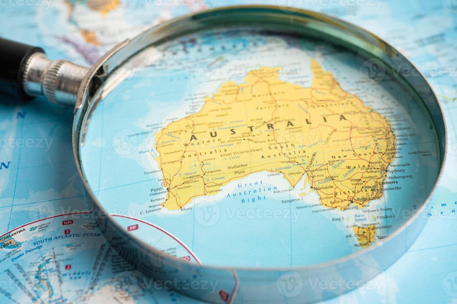 Bangkok, Thailand - June 15, 2024 East Australia, Magnifying glass close up with colorful world map, travel, geography, tourism and exploration. photo