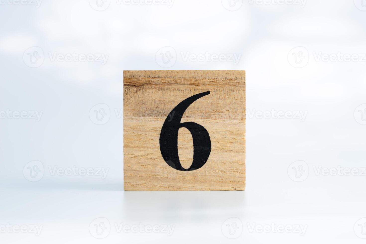 The number six written on a wooden cube, on a white background photo