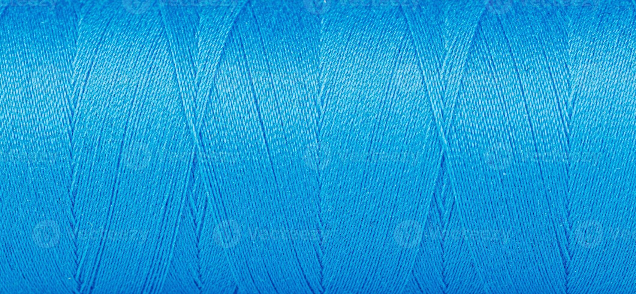 Texture of threads in a spool of blue color on a white background photo