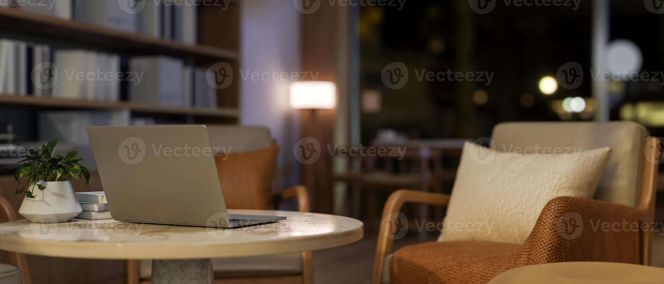 Close-up of a laptop on a table, surrounded by cozy armchairs in a contemporary coffee shop at night photo