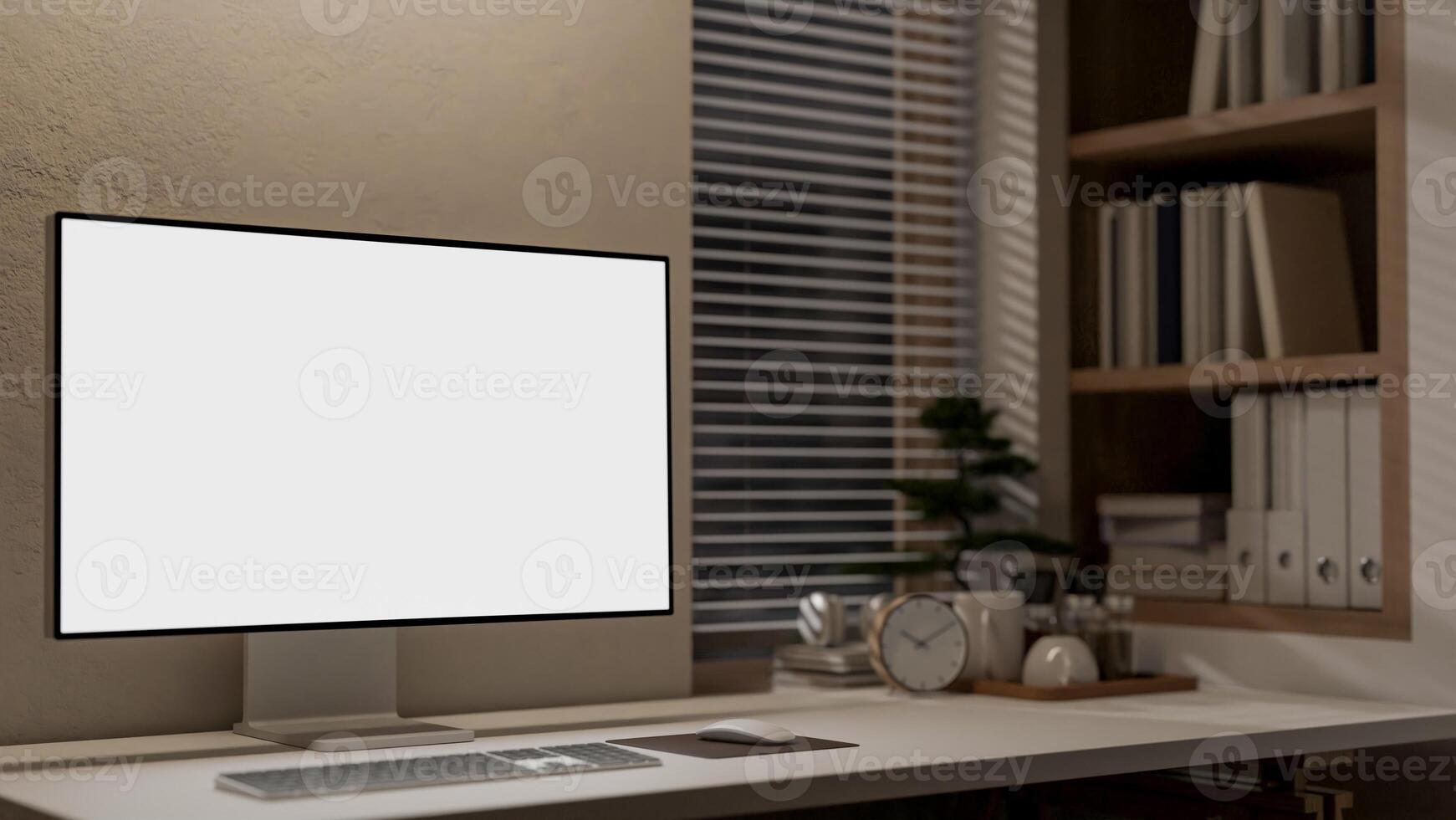 A computer with a white screen mockup on a table against the wall in a minimalist office at night. photo