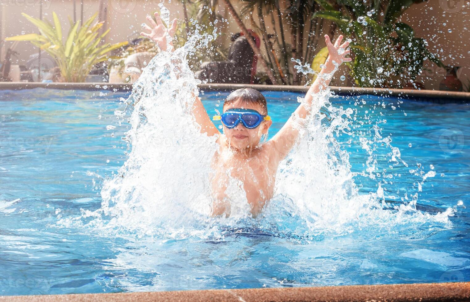 Boy jumping out of splashing water in pool photo