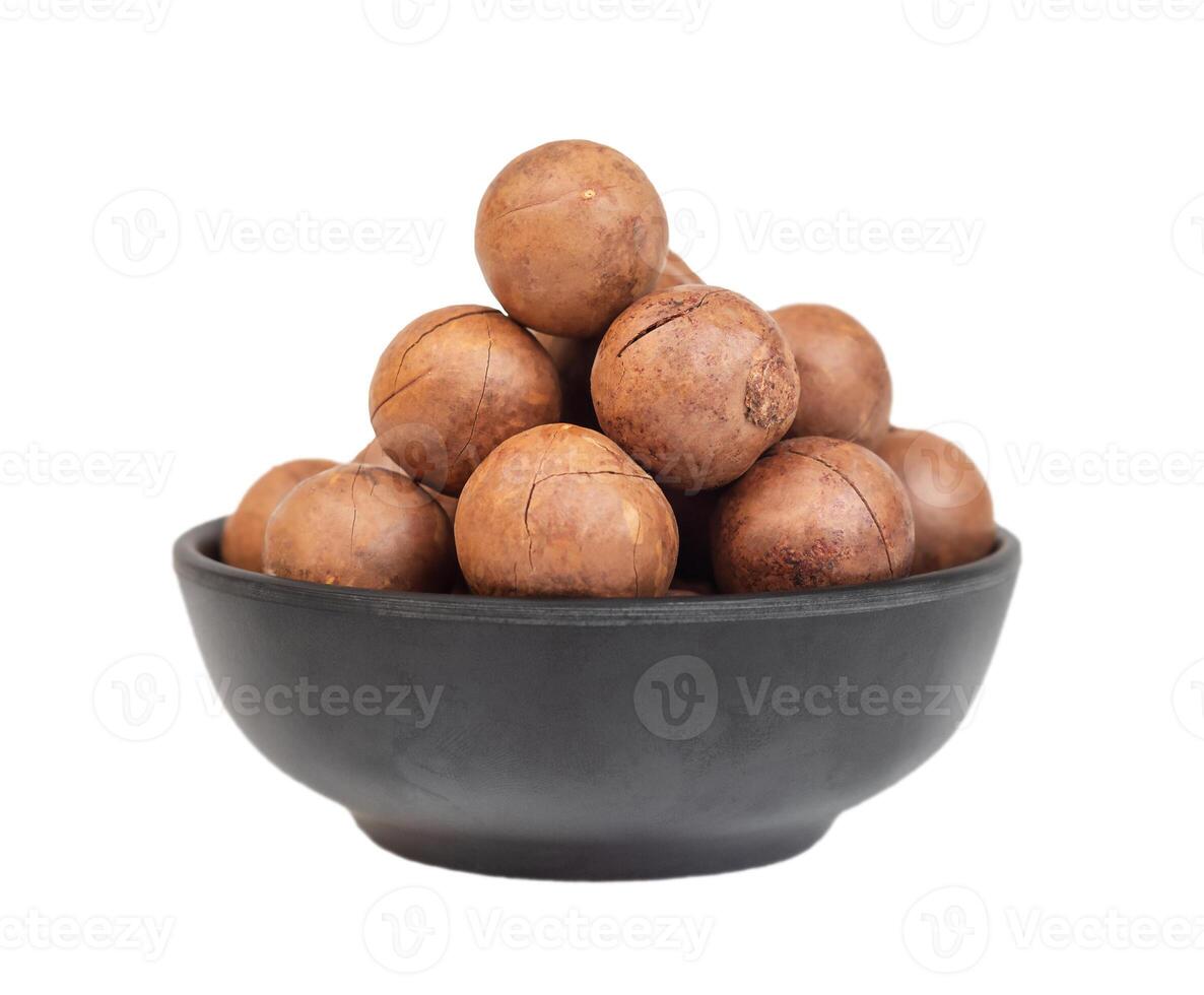 Heap of macadamia nuts in dark bowl isolated photo