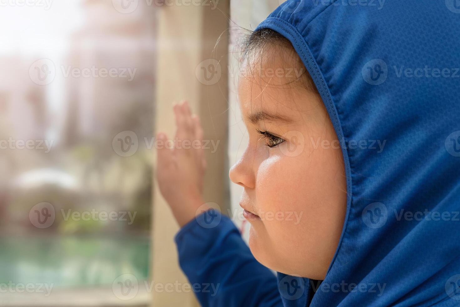 Sad child looks out the window photo