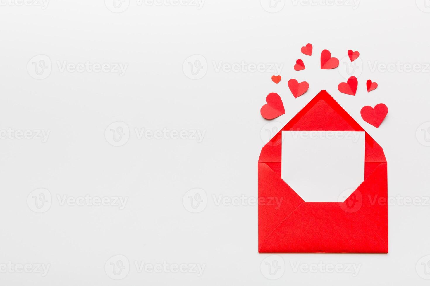 Red paper envelope with empty white card and heart on colored background. top view valentines day concept photo