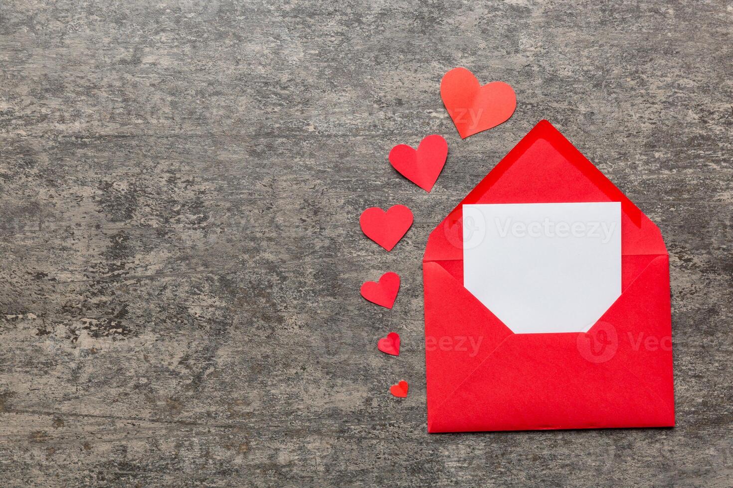 Red paper envelope with empty white card and heart on colored background. top view valentines day concept photo