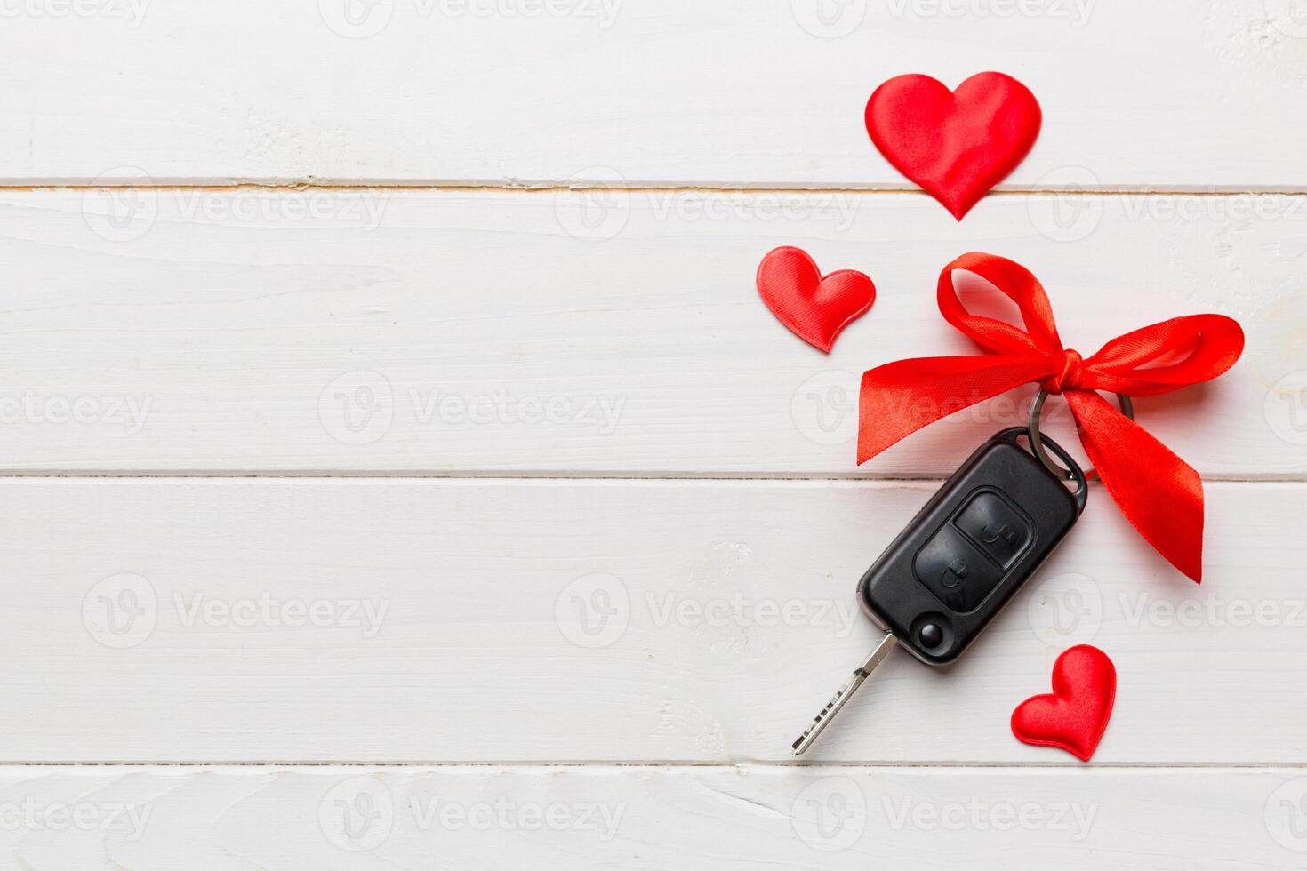 Car key with a red bow and a heart on Colored table. Giving present or gift for valentine day or christmas, Top view with copy space photo