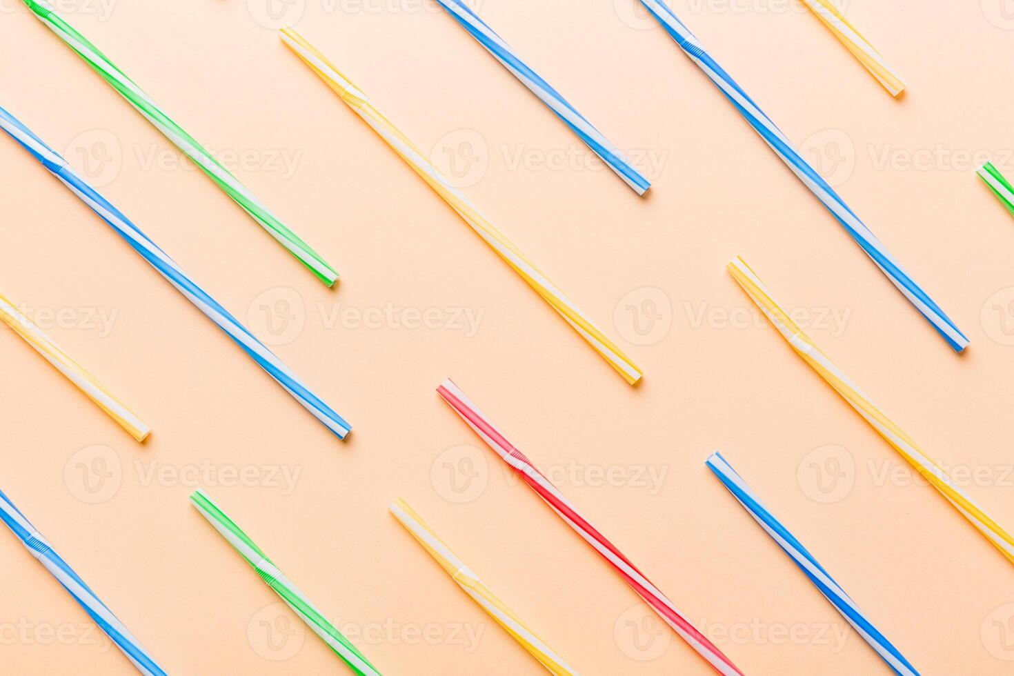 many multi-colored plastic tubes for cocktail on Colored background, top view photo