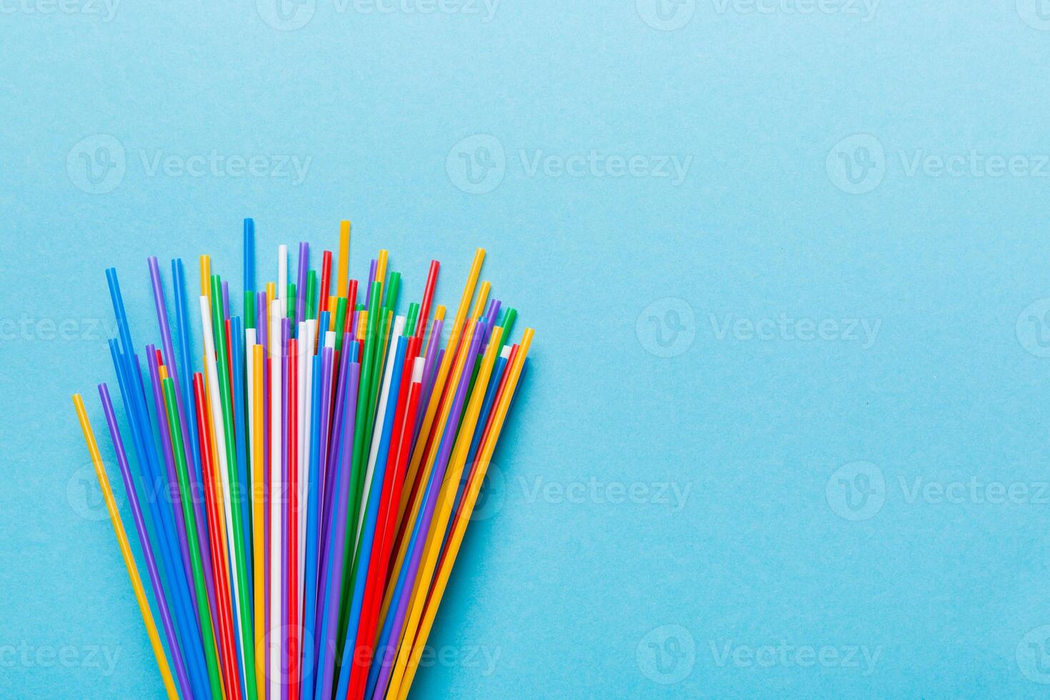 Heap of colorful plastic drinking straws on Colored background, flat lay. Copy Space for text photo