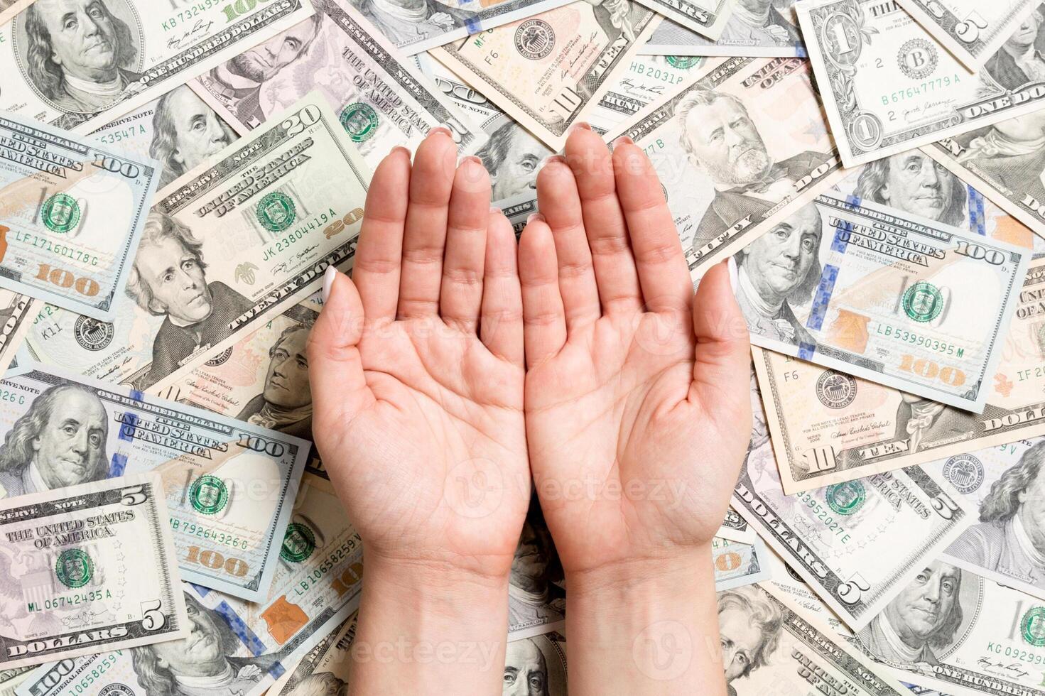 Top view of female hands on various dollar background. Wealth concept with empty space for your design. Begging money concept photo