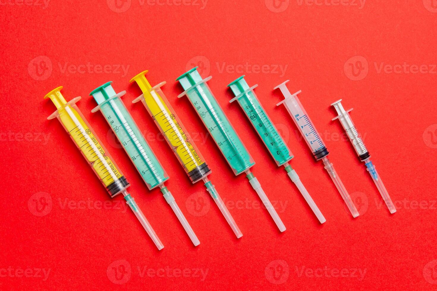 Top view of different syringes at red background. Medical injection concept with copy space photo