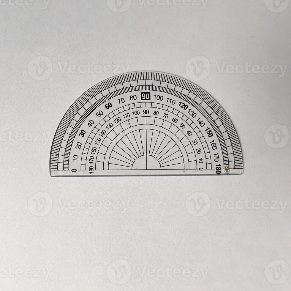 Close-up of a transparent protractor with a 0 to 180-degree scale, placed on a plain white background. This tool is commonly used for measuring angles photo