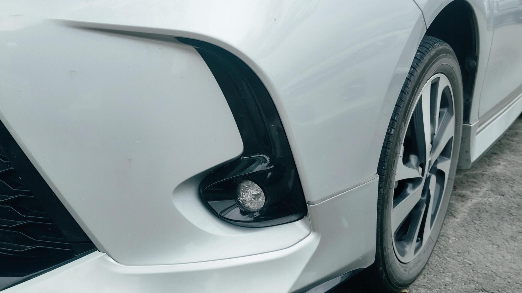 Close-up view of a modern white car's front fog light and tire, showcasing its sleek design photo