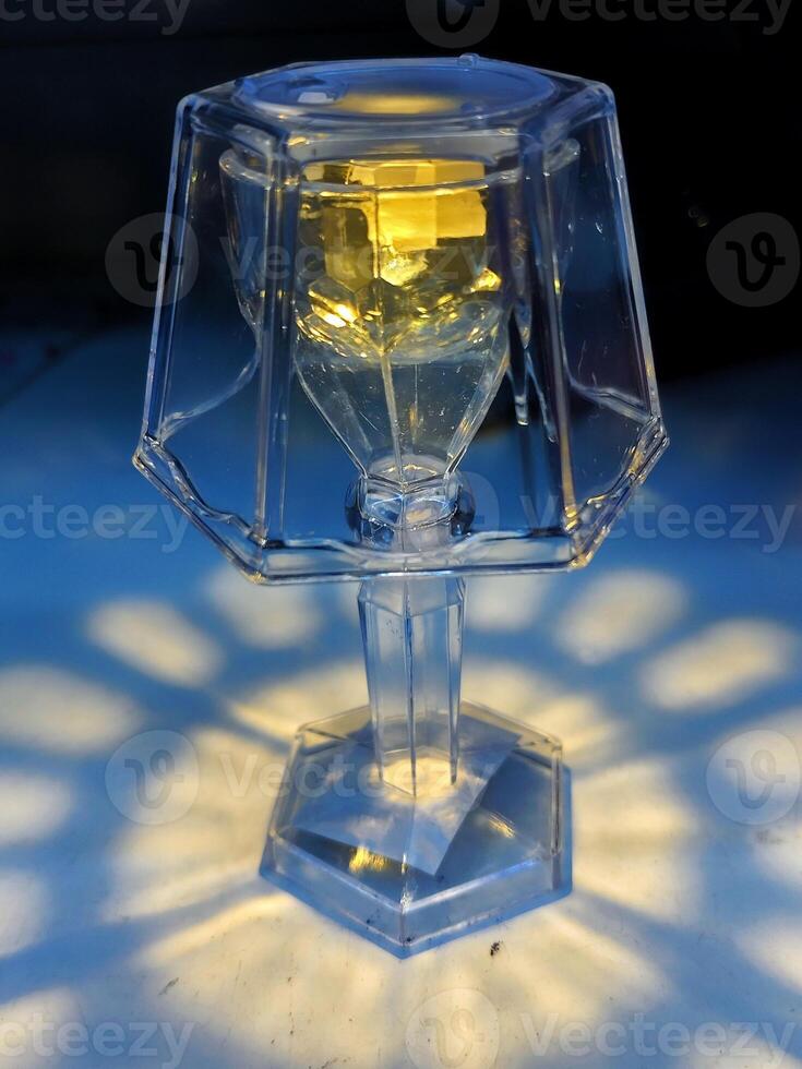 A beautiful glass lamp with intricate design casts stunning light patterns on the surface, perfect for concepts of elegance, ambiance, and interior decor photo