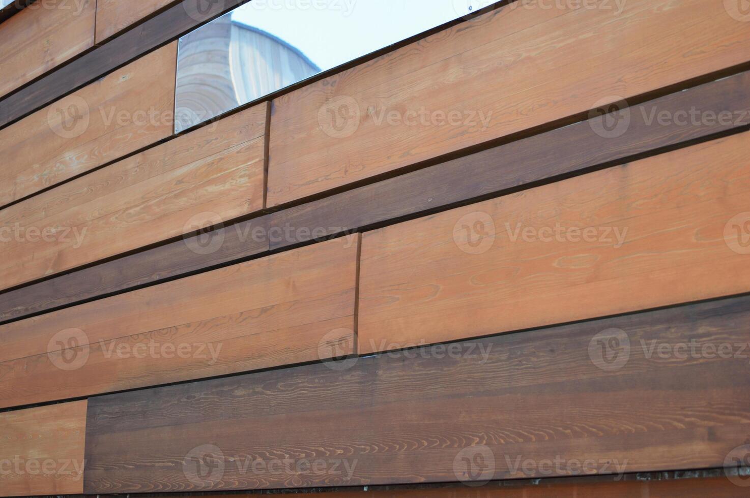 Decorative rectangular brown planks, wood and mirror panels in abstract pattern. Element of building facade. photo