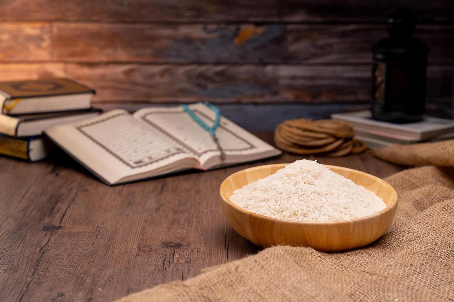Holy Quran and a grain of rice in a wooden bowl in the sack on a wooden table, Islamic zakat concept. Muslims to help the poor and needy. Conceptual shoot for property, income, and fitrah zakat. photo