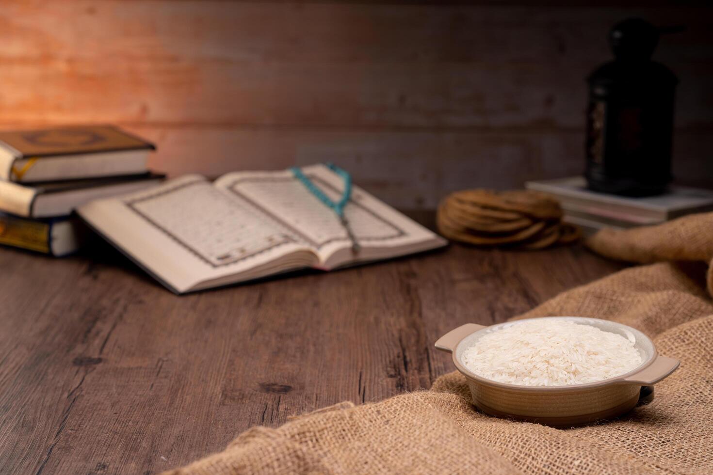Holy Quran and a grain of rice in a wooden bowl in the sack on a wooden table, Islamic zakat concept. Muslims to help the poor and needy. Conceptual shoot for property, income, and fitrah zakat. photo