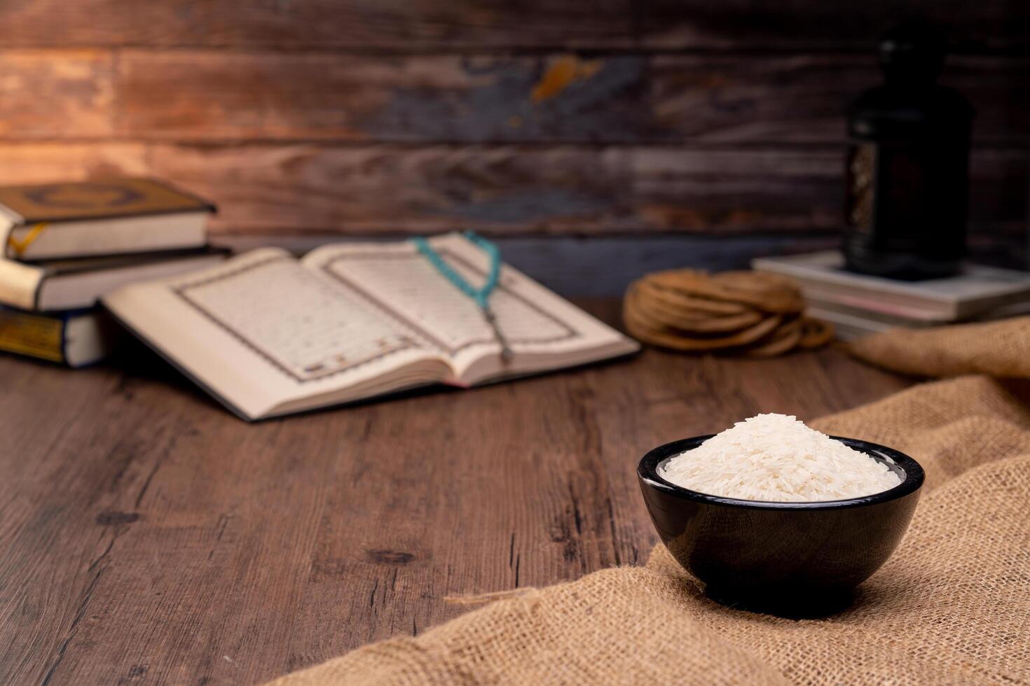 Holy Quran and a grain of rice in a wooden bowl in the sack on a wooden table, Islamic zakat concept. Muslims to help the poor and needy. Conceptual shoot for property, income, and fitrah zakat. photo