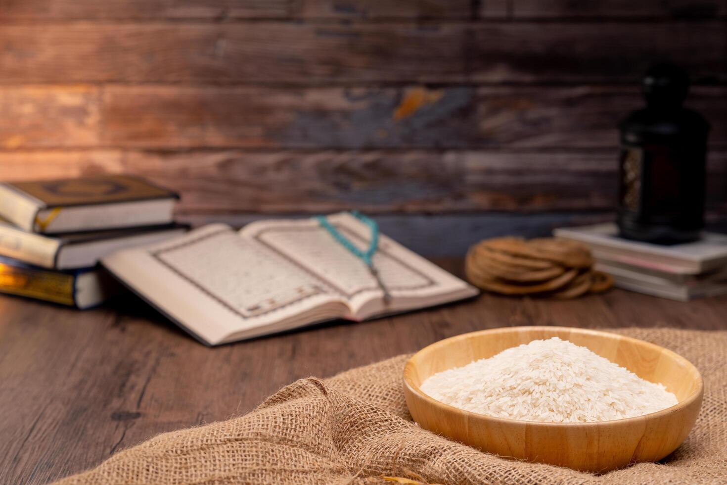 Holy Quran and a grain of rice in a wooden bowl in the sack on a wooden table, Islamic zakat concept. Muslims to help the poor and needy. Conceptual shoot for property, income, and fitrah zakat. photo