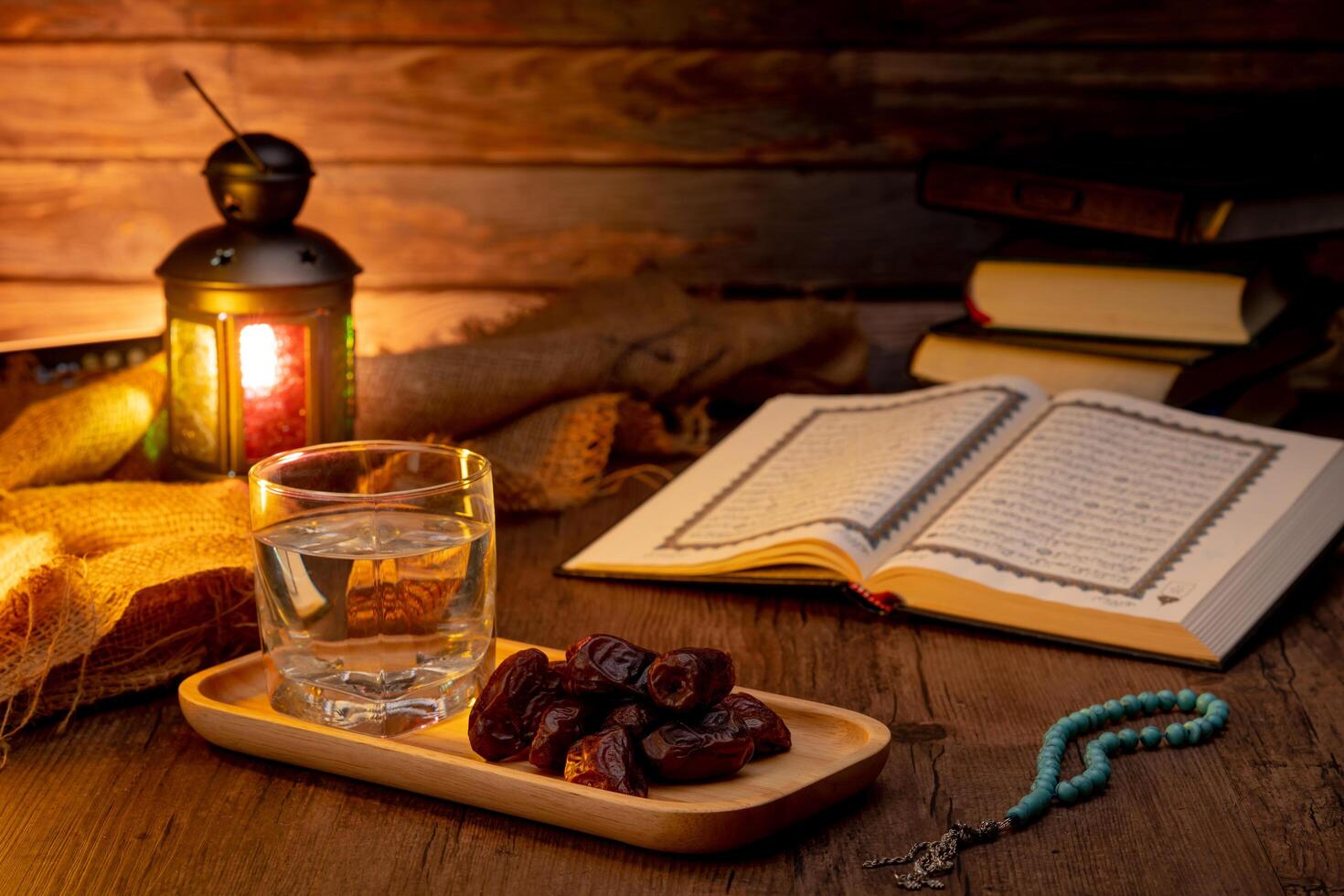 Many Date Palms are on bowls, plates, a cup of water, and the Quran, islamic style lamps on wooden tables, to wait for the time of Iftar, with the concept of ramadan Muslims around the world. photo