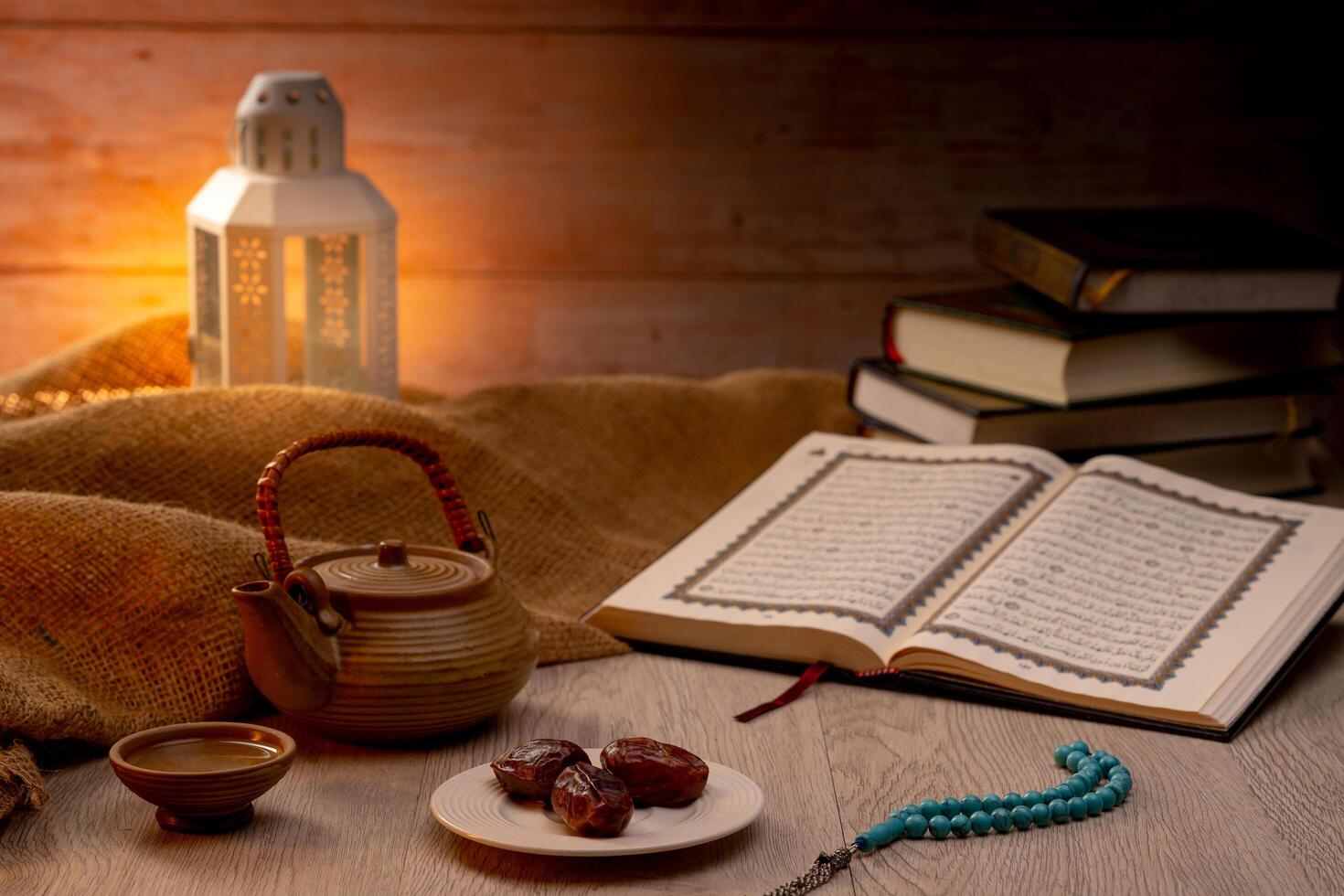 Many Date Palms are on bowls, plates, a cup of water, and the Quran, islamic style lamps on wooden tables, to wait for the time of Iftar, with the concept of ramadan Muslims around the world. photo
