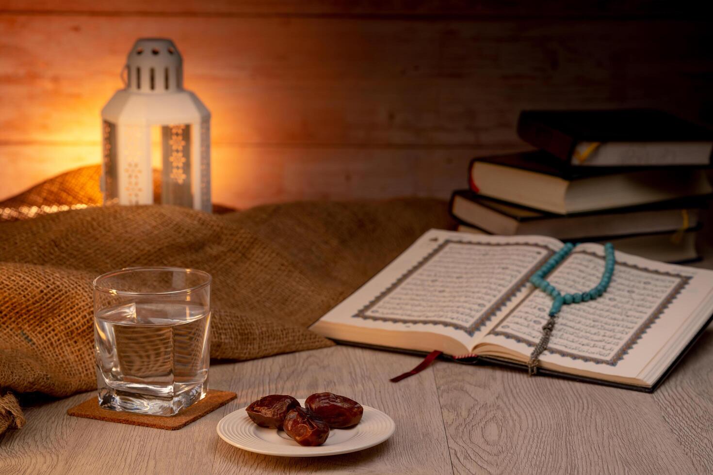 Many Date Palms are on bowls, plates, a cup of water, and the Quran, islamic style lamps on wooden tables, to wait for the time of Iftar, with the concept of ramadan Muslims around the world. photo