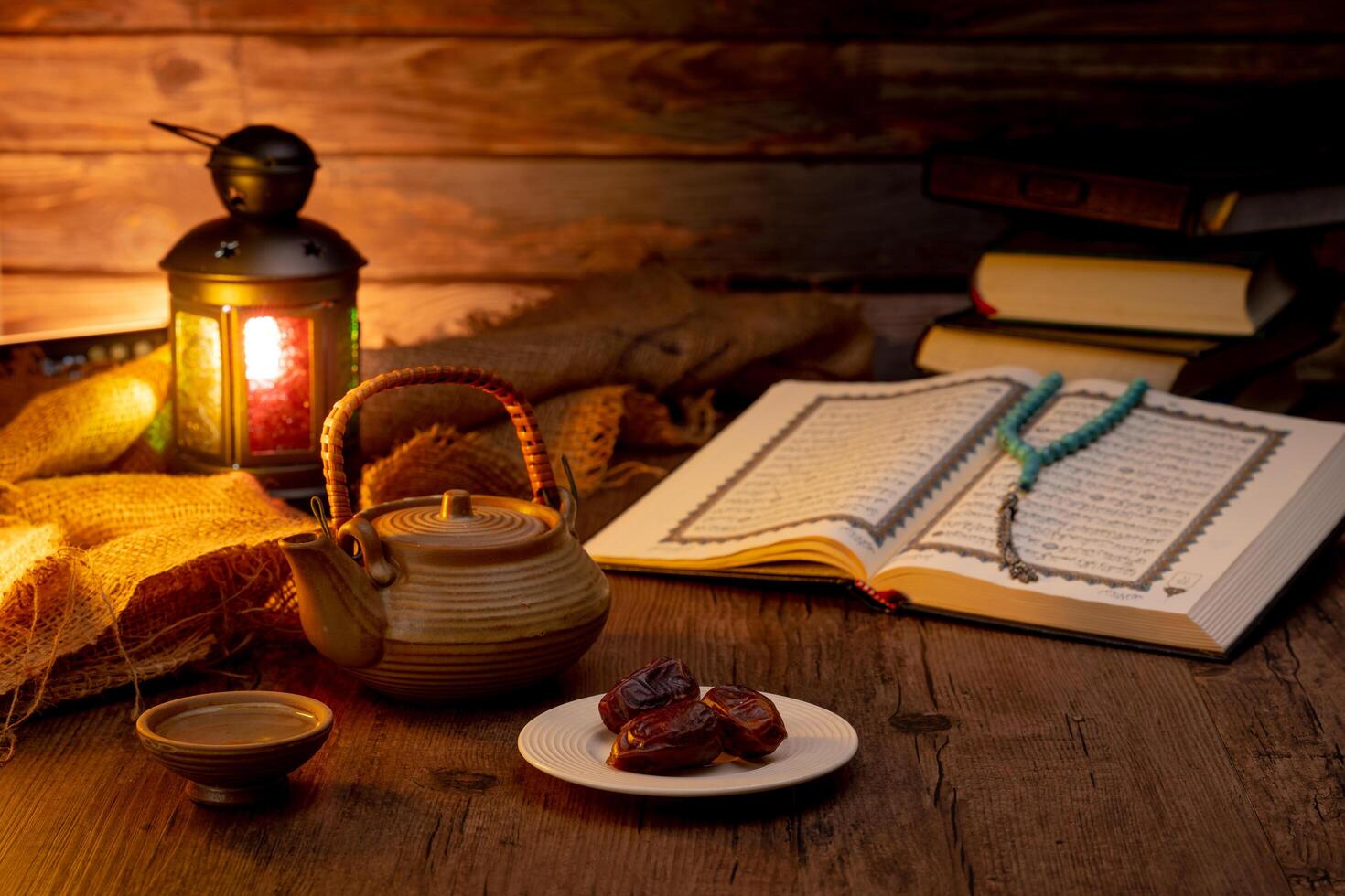 Many Date Palms are on bowls, plates, a cup of water, and the Quran, islamic style lamps on wooden tables, to wait for the time of Iftar, with the concept of ramadan Muslims around the world. photo