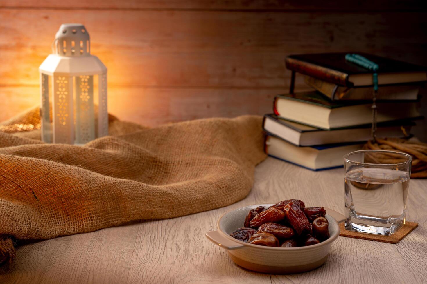 Many Date Palms are on bowls, plates, a cup of water, and the Quran, islamic style lamps on wooden tables, to wait for the time of Iftar, with the concept of ramadan Muslims around the world. photo