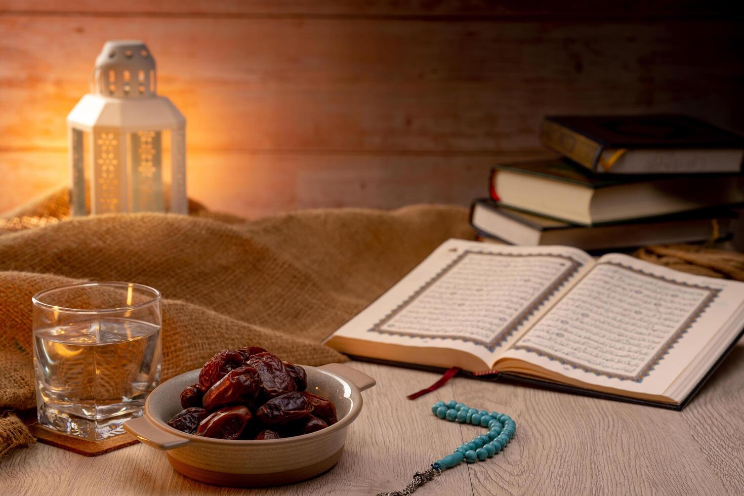 Many Date Palms are on bowls, plates, a cup of water, and the Quran, islamic style lamps on wooden tables, to wait for the time of Iftar, with the concept of ramadan Muslims around the world. photo