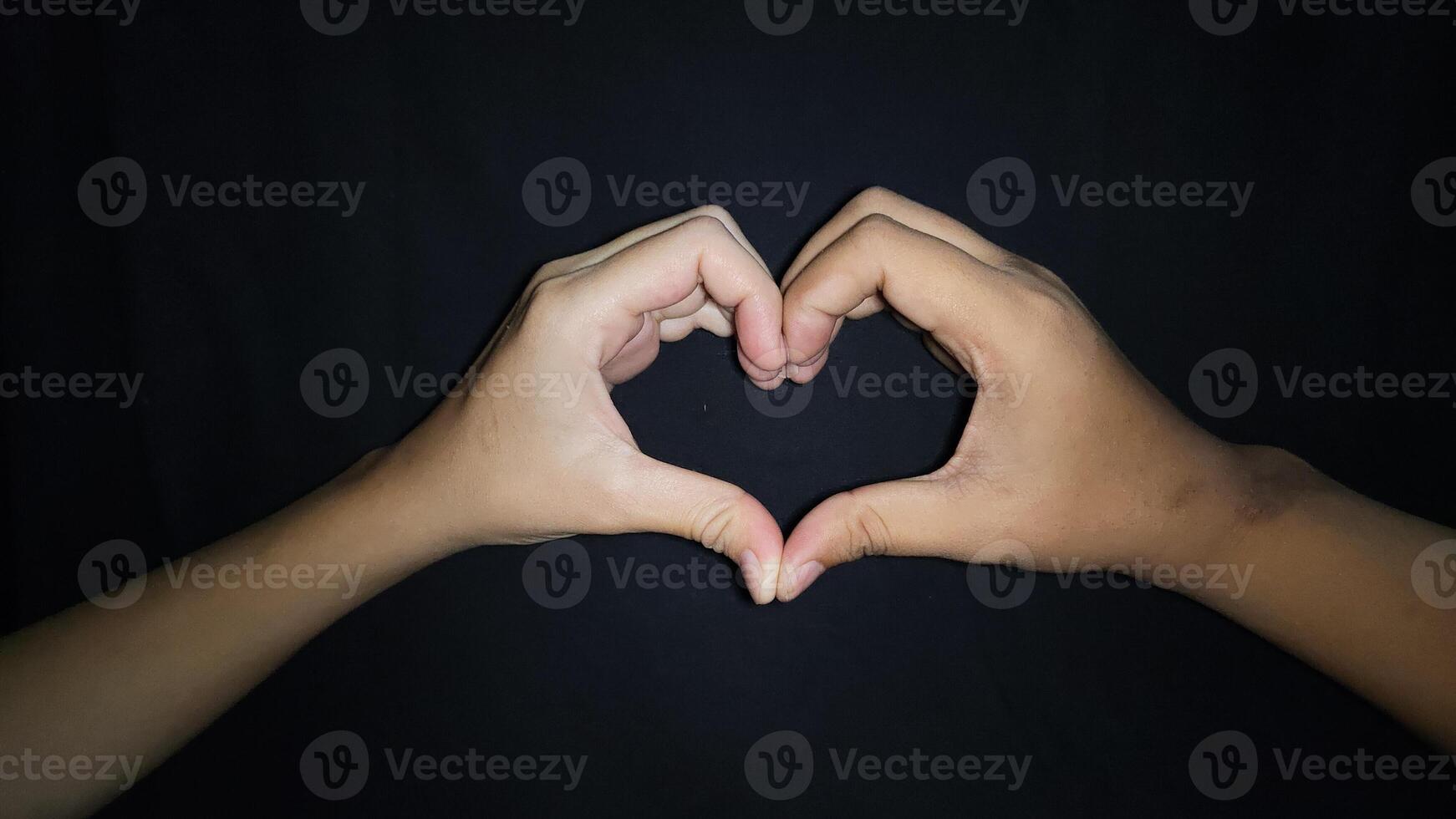 Two hands of lovers forming a heart.Isolated on black background photo