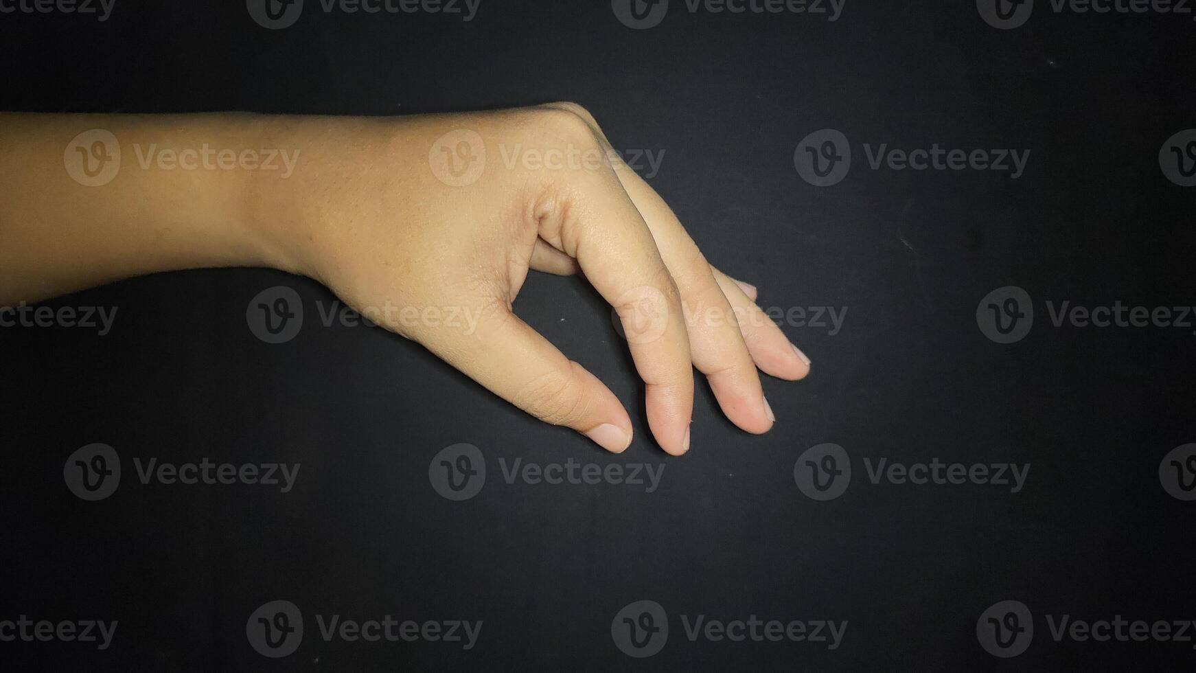Hand by showing a gesture of taking an item or something small. Isolated on black background photo