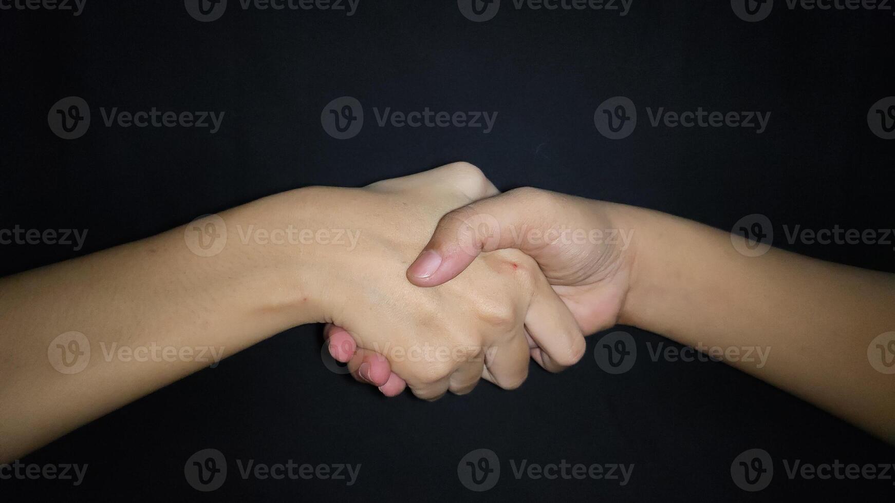 Hands shaking between a man and a woman. Isolated on black background photo
