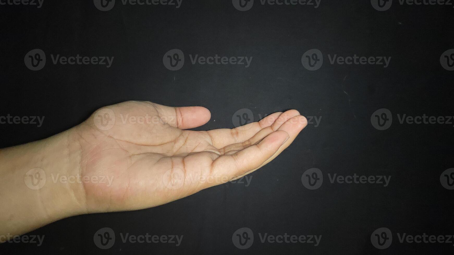 The hand is raised showing a gesture of asking for something. Isolated on black background photo