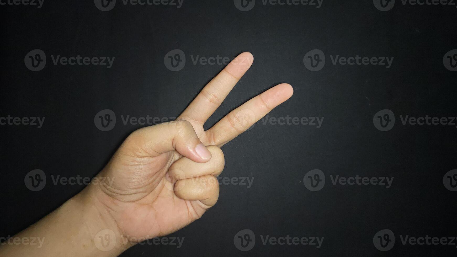 Hand with two fingers up means peace. Isolated on black background photo