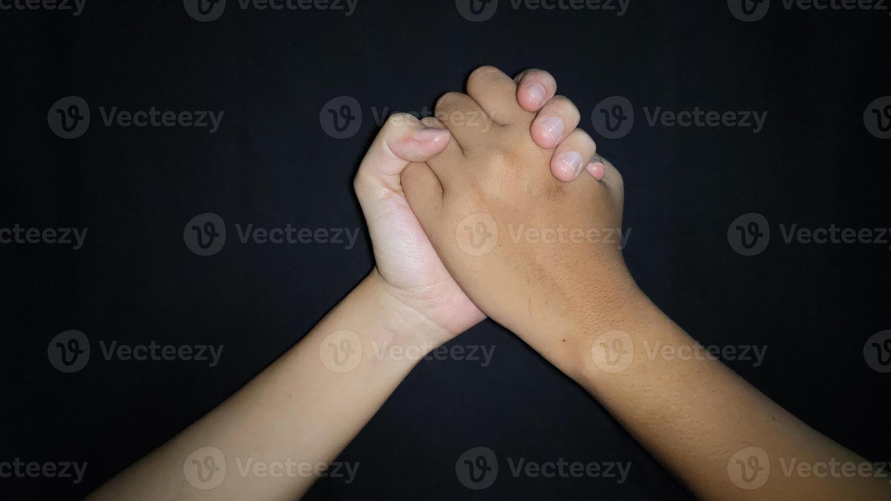 Two hands shaking which means friendship.Isolated on black background photo