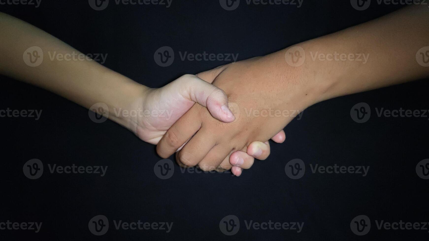 Hands shaking between a man and a woman. Isolated on black background photo