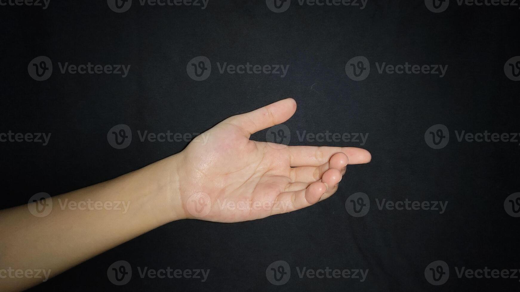 Hand with a gesture offering help isolated on black background photo