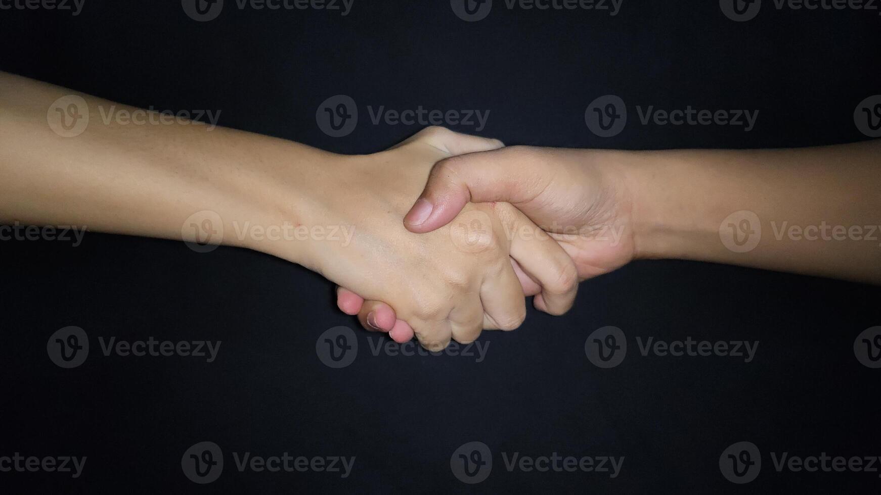 Hands shaking between a man and a woman. Isolated on black background photo