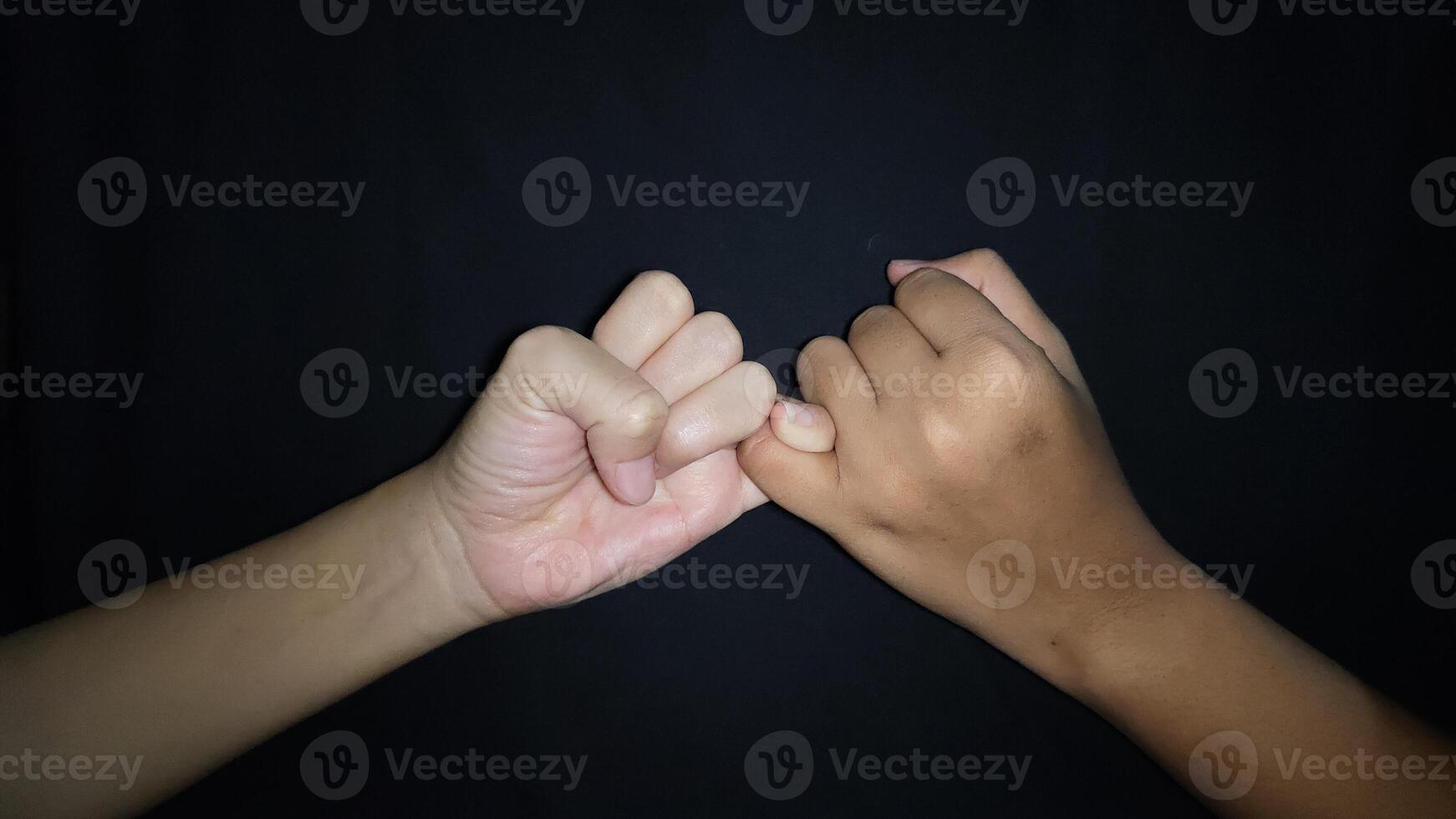 Two hands with a gesture showing the promise of the little finger.Isolated on black background photo