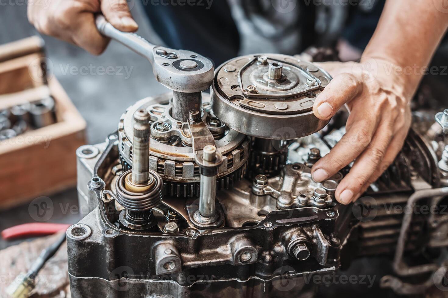 Motorcycle mechanic use ratchet wrench and socket to repair motorcycle engine,working at garage, maintenance and repair motorcycle concept photo