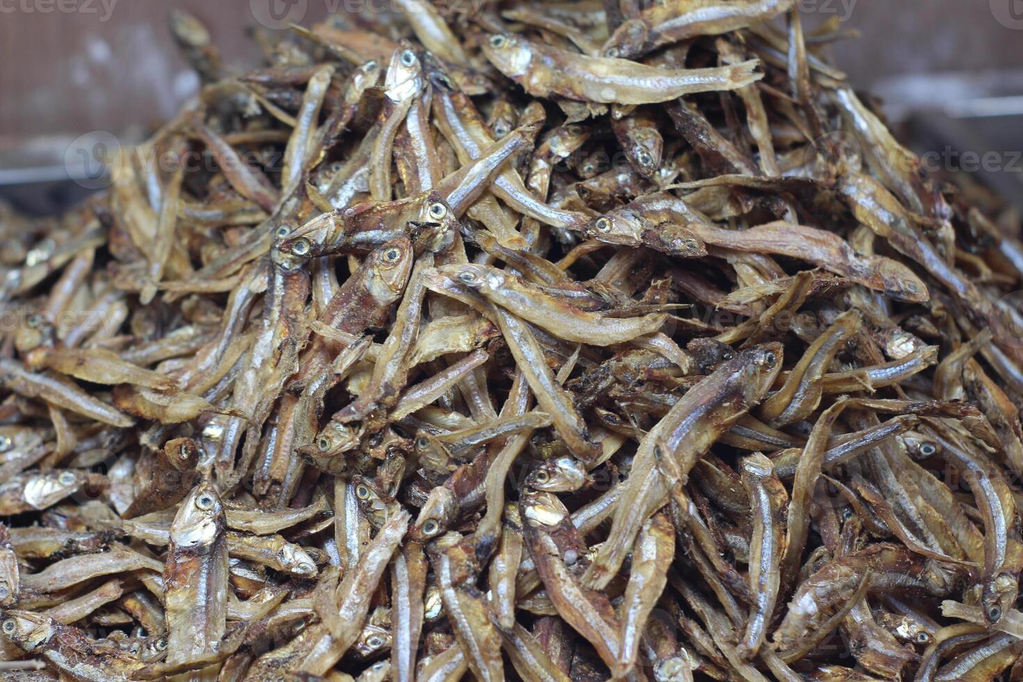 Dried fish display in a seafood market. Fish that is being dried in the sun to be salted fish and sold. Salted Anchovies in one large tray. Heap of dried peeled anchovies photo